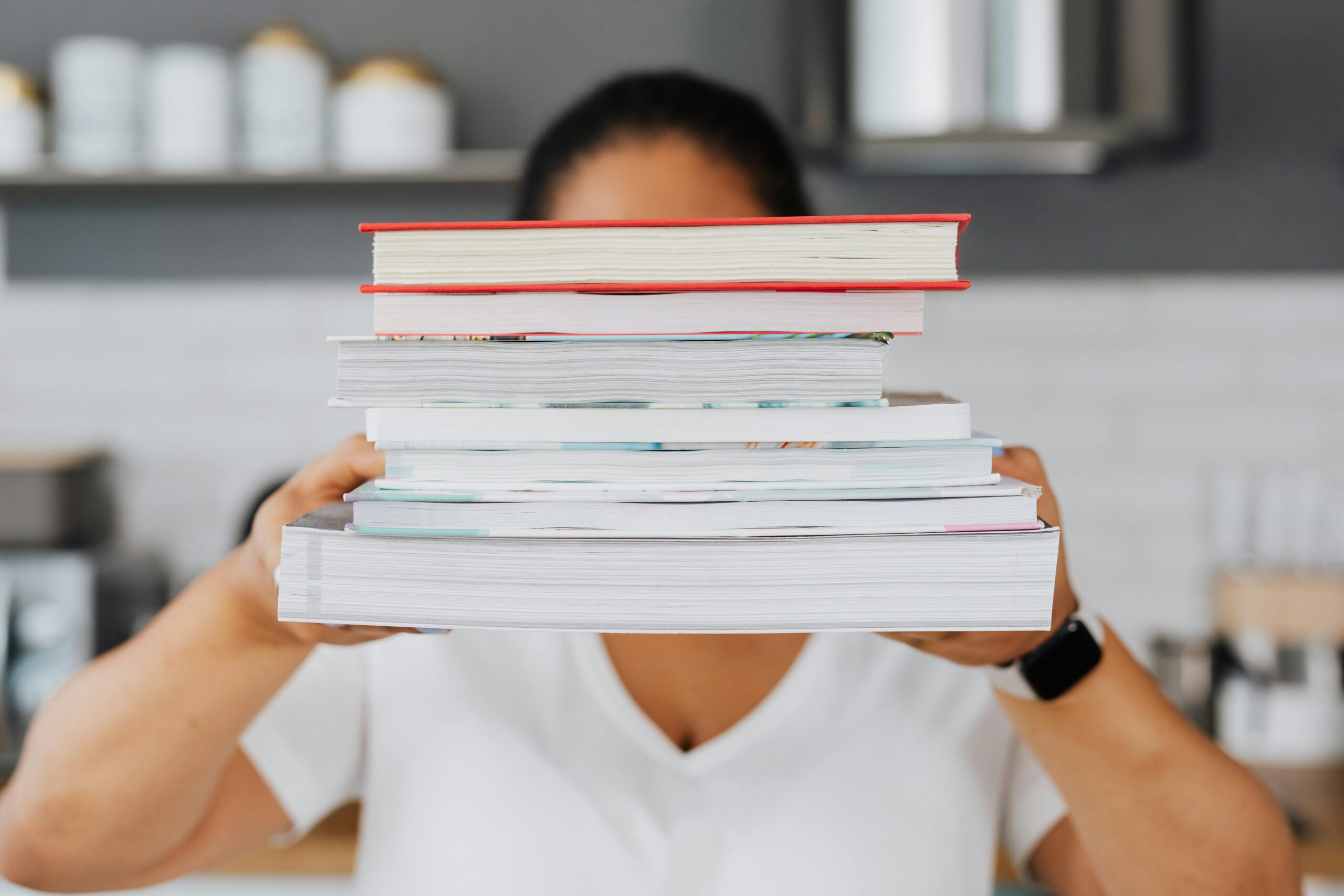 Close-up of a person holding a stack of books indoors, showcasing academic focus.