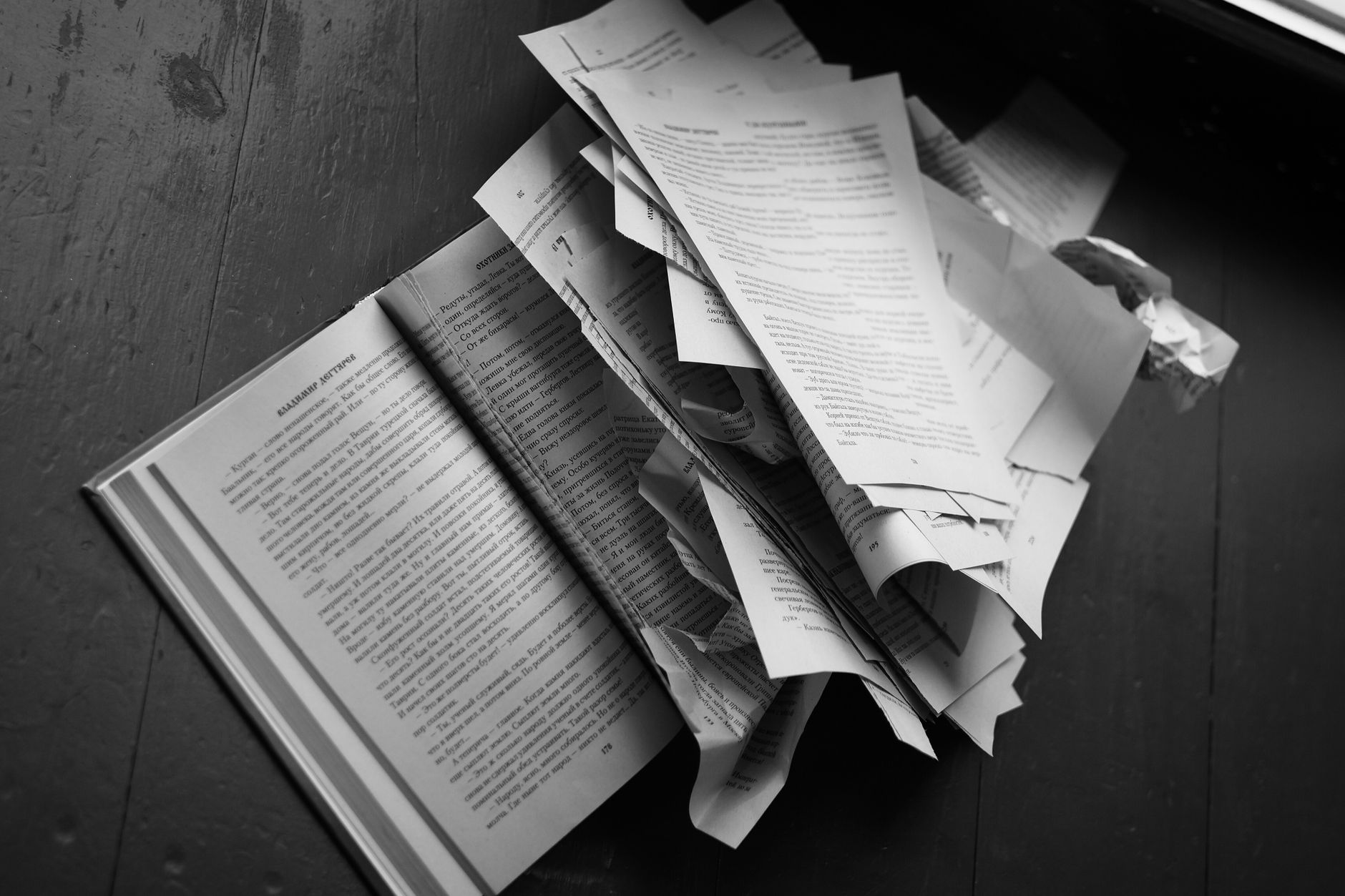 black and white torn book pages on wooden floor
