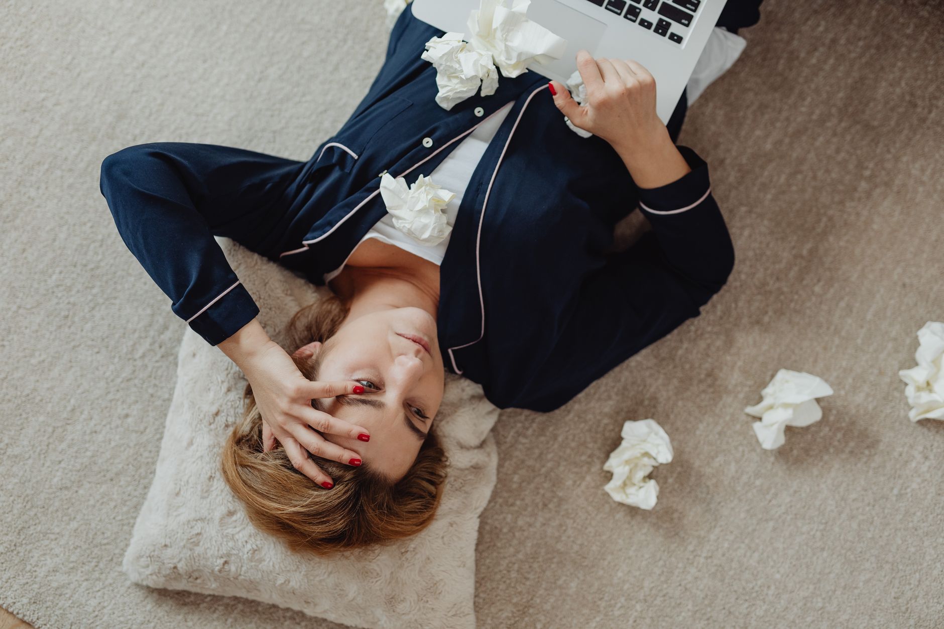 sad woman lying with used tissue scattered on the floor